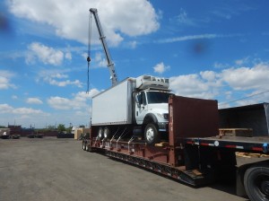 White box truck loaded onto a flat rack